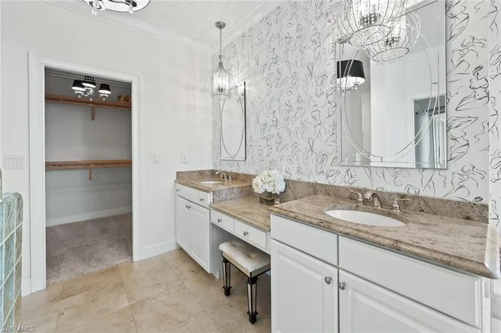 Bathroom featuring a spacious closet, double vanity, ornamental molding, wallpapered walls, and light carpet