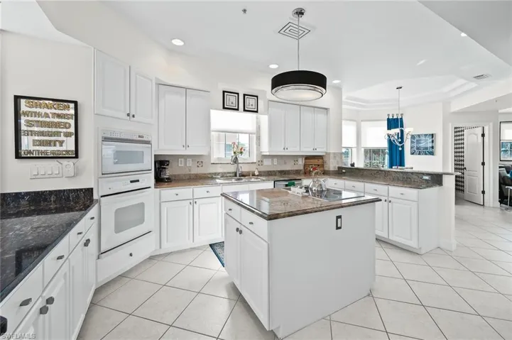 Kitchen featuring a tray ceiling, white cabinets, hanging light fixtures, and light tile patterned flooring
