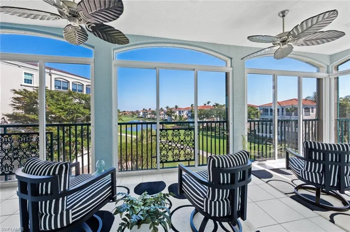 Sunroom with a textured wall, tile patterned floors, a residential view, and a water view