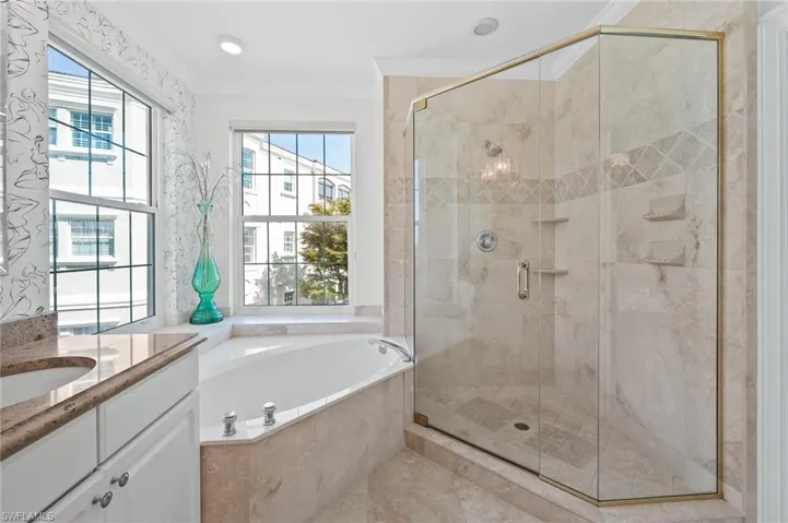 Bathroom with vanity, a garden tub, a stall shower, and ornamental molding