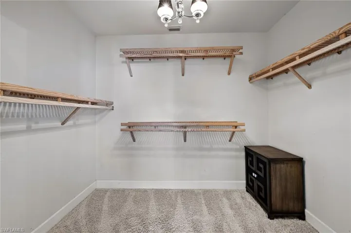 Walk in closet featuring light carpet and a chandelier