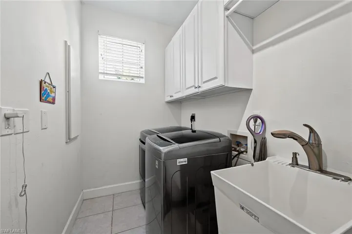 Laundry room featuring light tile patterned floors, cabinet space, and washing machine and dryer