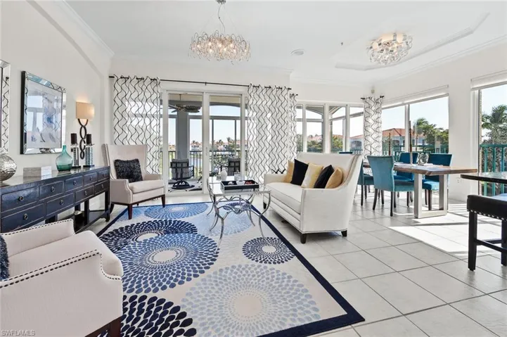 Living area featuring suspended lighting, light tile patterned flooring, and ornamental molding
