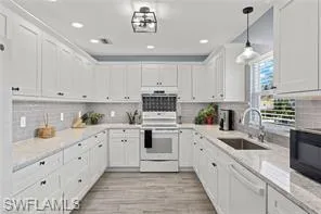 Kitchen featuring white appliances, white cabinetry, tasteful backsplash, light wood finished floors, and recessed lighting