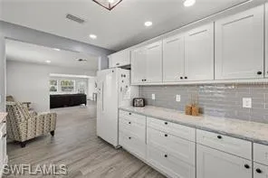 Kitchen featuring white cabinetry, light wood-style floors, backsplash, recessed lighting, and open floor plan