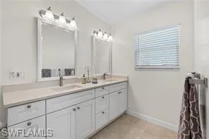 Full bath with double vanity and baseboards