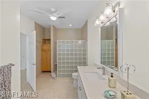 Full bath featuring double vanity, ceiling fan, and tile patterned flooring