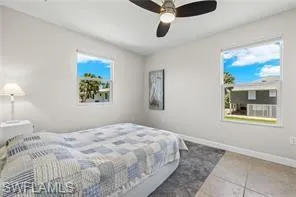 Tiled bedroom with multiple windows and a ceiling fan