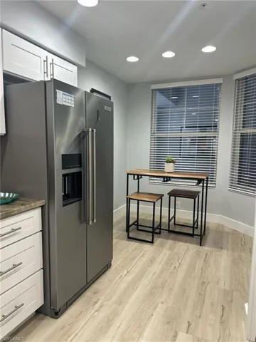 Kitchen featuring stainless steel fridge, light wood-type flooring, white cabinetry, and recessed lighting