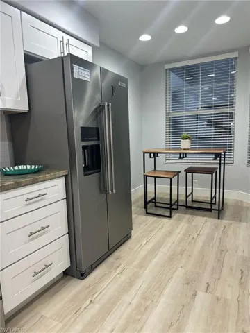 Kitchen featuring stainless steel fridge with ice dispenser, light wood-type flooring, white cabinets, and recessed lighting