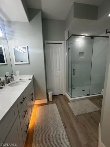 Bathroom with a stall shower, double vanity, and wood finished floors