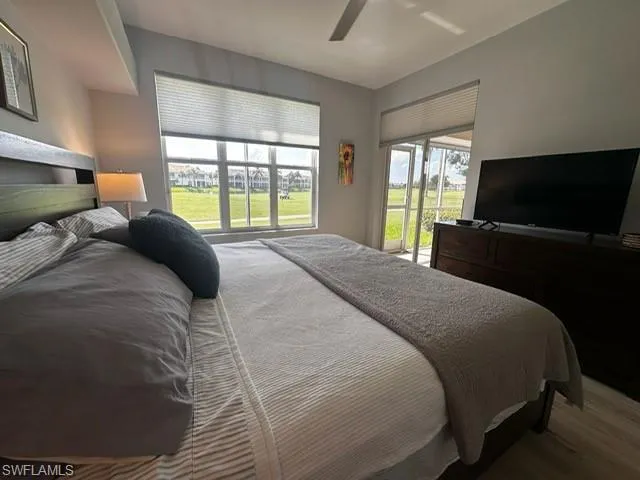 Bedroom with ceiling fan, wood finished floors, and access to exterior