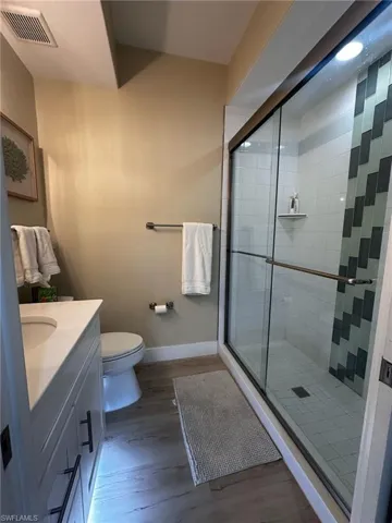 Full bathroom with wood finished floors, a stall shower, and vanity