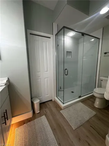 Full bathroom with a shower stall, vanity, and wood finished floors