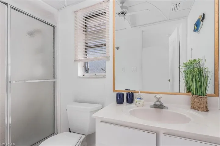 Bathroom featuring a shower with door, vanity, and toilet