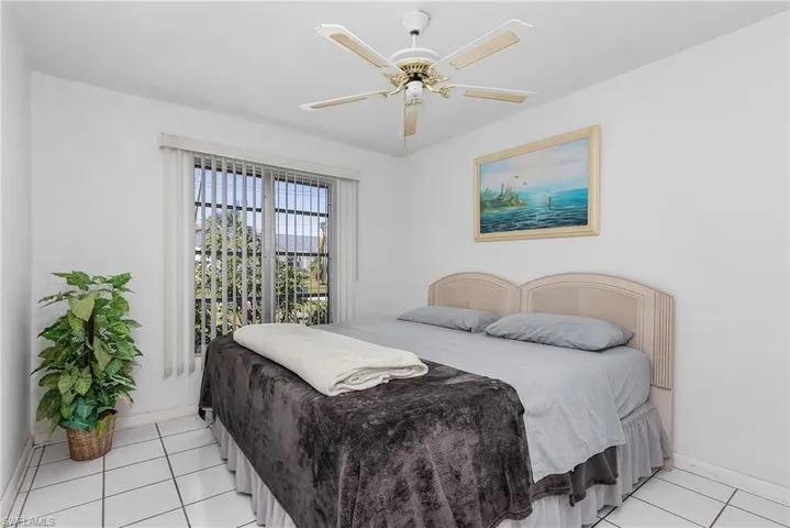 Bedroom with ceiling fan and light tile floors