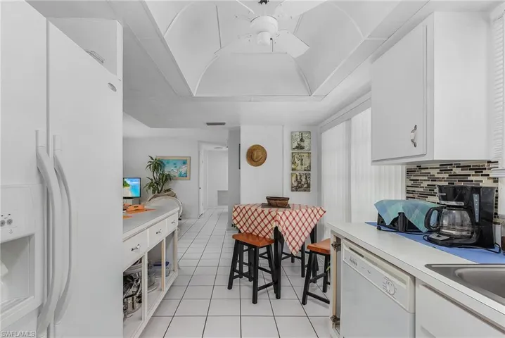 Kitchen featuring white appliances, white cabinets, backsplash, and light tile flooring