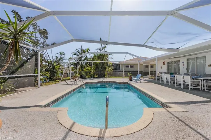 View of pool featuring a patio area and glass enclosure