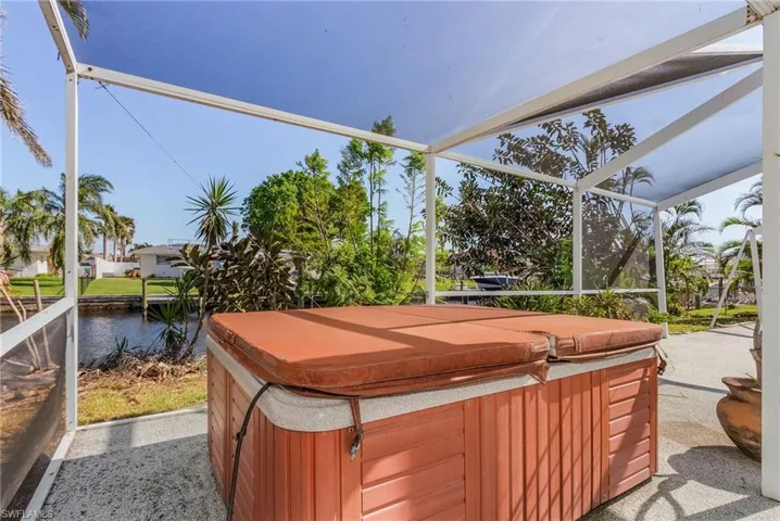 View of patio with a hot tub, a lanai, and a water view