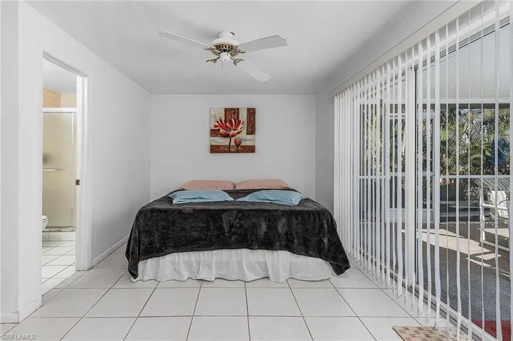 Bedroom featuring ensuite bath, ceiling fan, and light tile floors