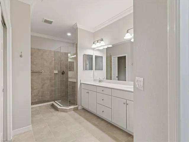 Owners Bathroom featuring walk in shower, tile flooring, vanity with extensive cabinet space, and dual sinks