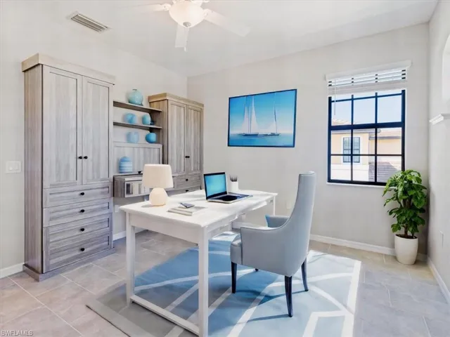 3rd bedroom featuring light tile flooring and ceiling fan and built in desk. virtually staged