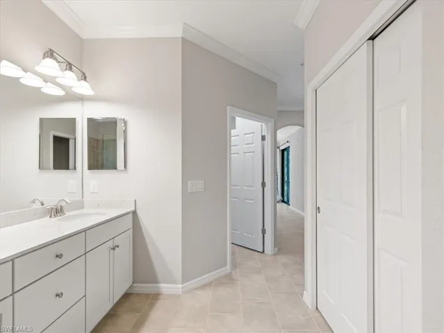 Bathroom featuring tile flooring, ornamental molding, and vanity