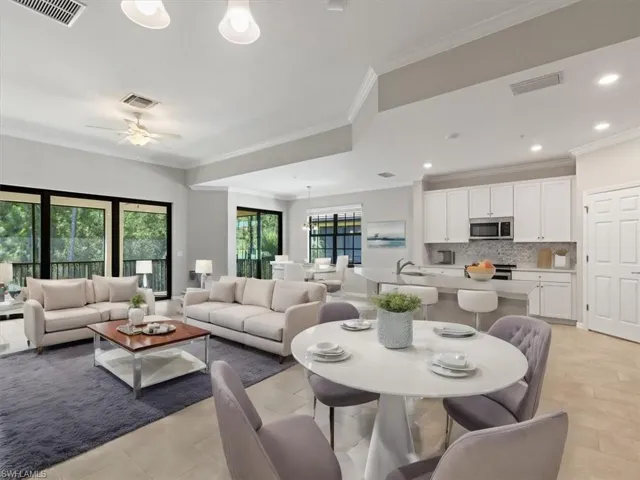 Spacious great room with volume ceiling,  ceiling fan, light tile flooring, and crown molding.  Virtually Staged