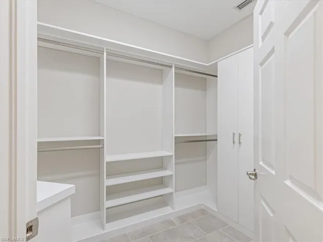 Walk in closet with light tile floors