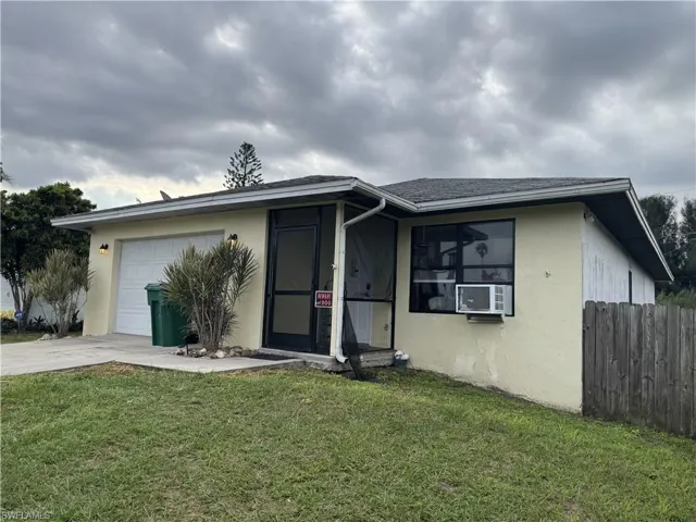 View of front of property featuring cooling unit, a front lawn, and a garage