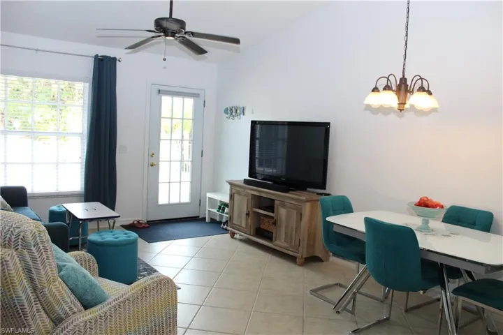 Tiled living room featuring ceiling fan with notable chandelier and a wealth of natural light