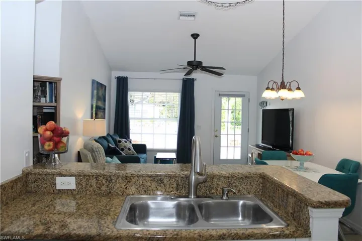 Kitchen featuring ceiling fan with notable chandelier, hanging light fixtures, lofted ceiling, and sink