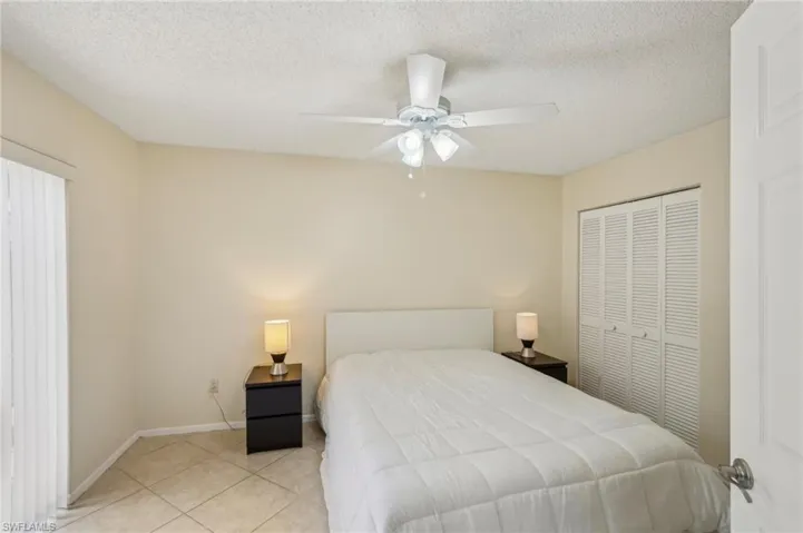 Tiled bedroom with a ceiling fan, a textured ceiling, and a closet