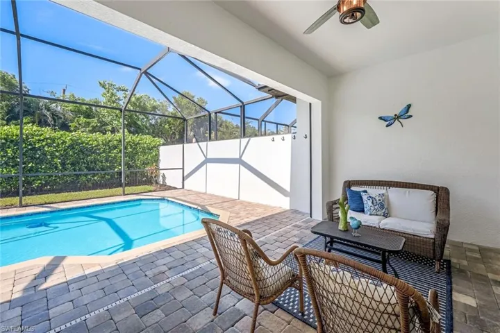 View of pool featuring ceiling fan, glass enclosure, and a patio
