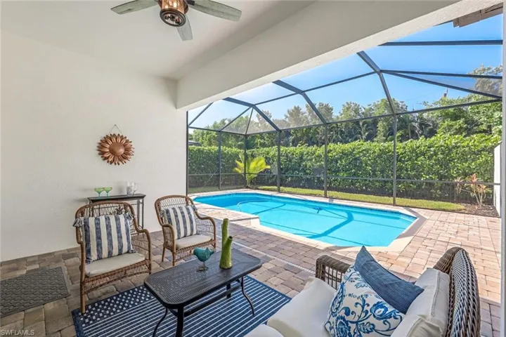 View of swimming pool featuring outdoor lounge area, glass enclosure, a patio area, and ceiling fan