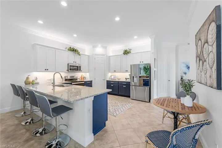 Kitchen with sink, light stone counters, white cabinetry, and appliances with stainless steel finishes