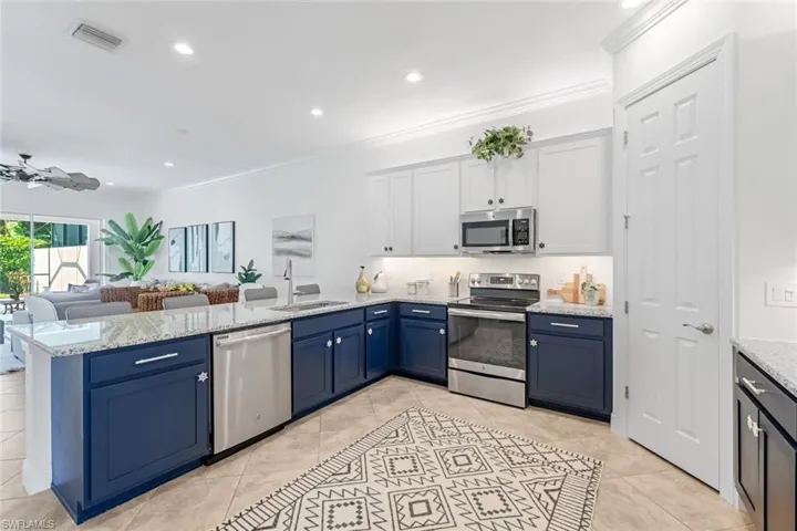 Kitchen with stainless steel appliances, blue cabinetry, kitchen peninsula, sink, and ceiling fan