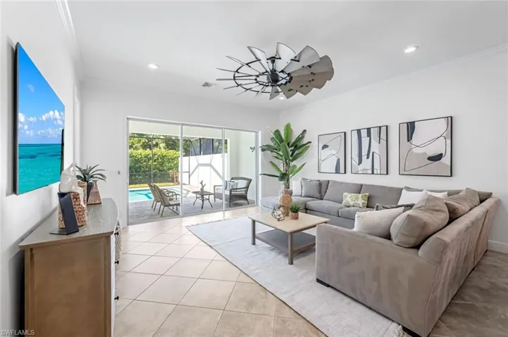 Tiled living room featuring ornamental molding and ceiling fan