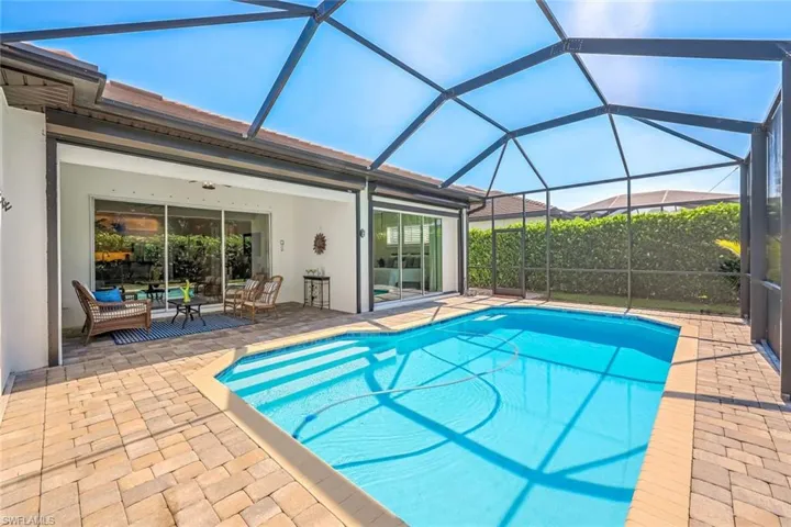 View of pool featuring a patio and glass enclosure