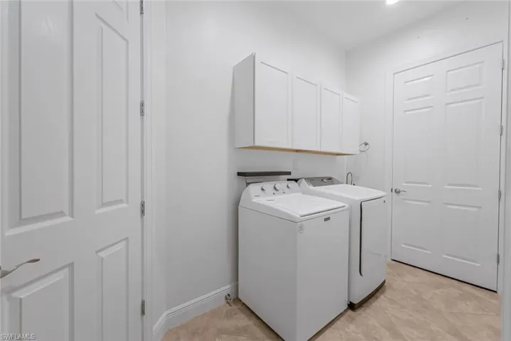 Laundry area with washer and dryer, cabinets, and light tile floors