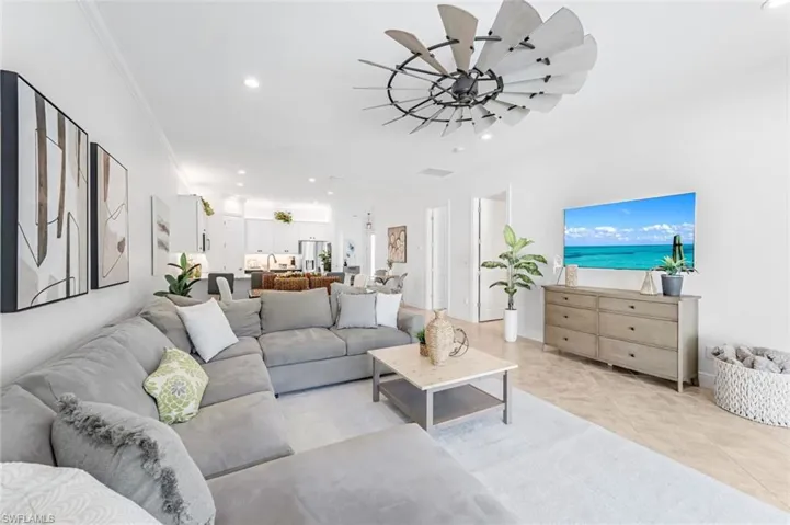 Tiled living room featuring ceiling fan and crown molding