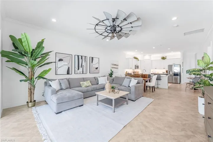 Living room featuring ceiling fan, light tile floors, and crown molding