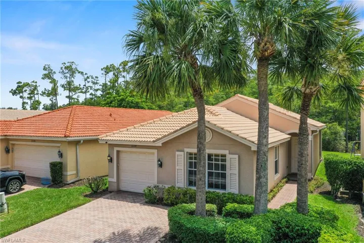 Single-story residence featuring a neutral stucco exterior, tile roof, and a paved driveway leading to an attached garage