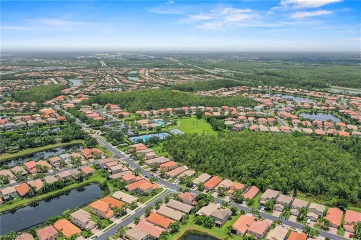 Expansive aerial showcasing a residential community with numerous single-story homes featuring terracotta-style roofs
