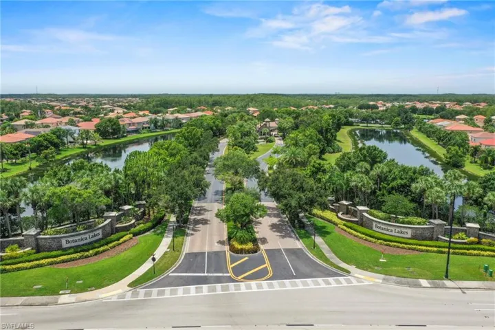 Botanica Lakes community entrance featuring stone signage, mature landscaping, and dual lakes