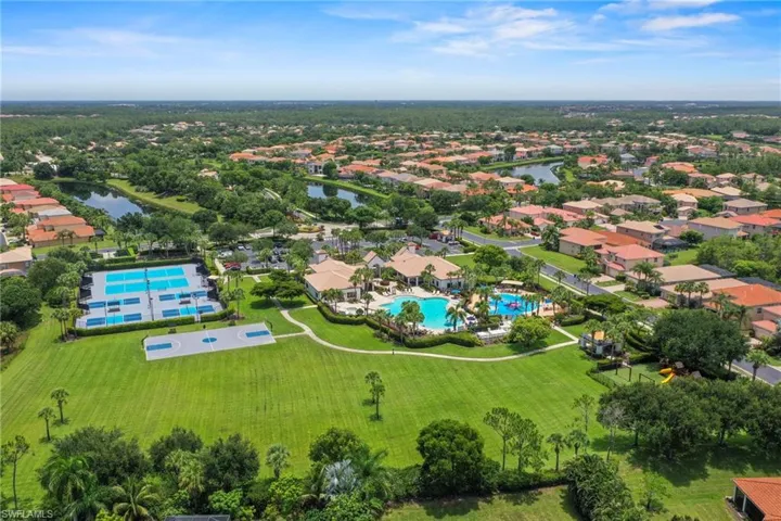 Aerial overview of a community featuring a clubhouse with multiple swimming pools, extensive tennis courts, and a basketball court