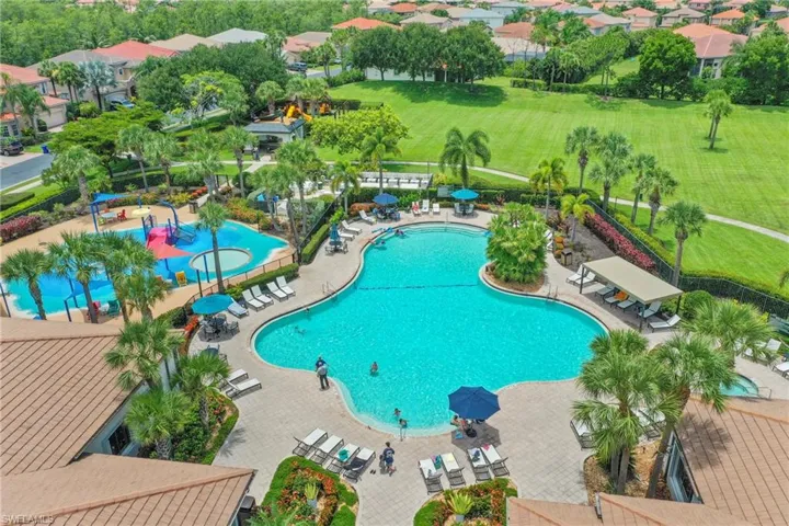 Expansive community amenity area featuring a large free-form swimming pool, separate splash pad, spa, and shaded lounge areas