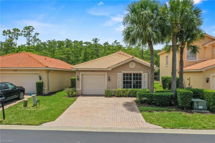Single-story residence featuring a terracotta tile roof, paver driveway, an attached garage, and decorative window shutters