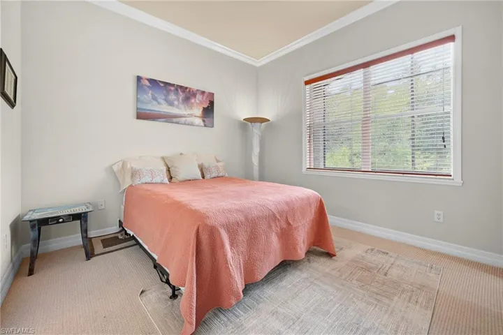 Carpeted room featuring a large window with white framing and integrated blinds, crown molding, and neutral wall paint