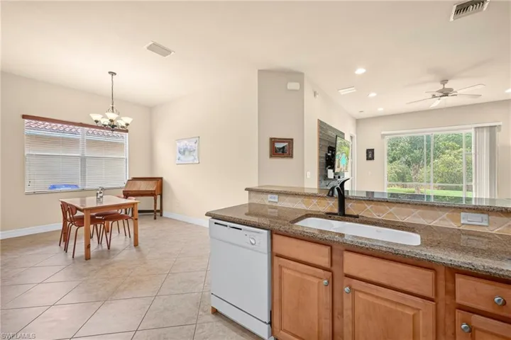 Kitchen with wood cabinetry, granite countertops, and a tile backsplash
